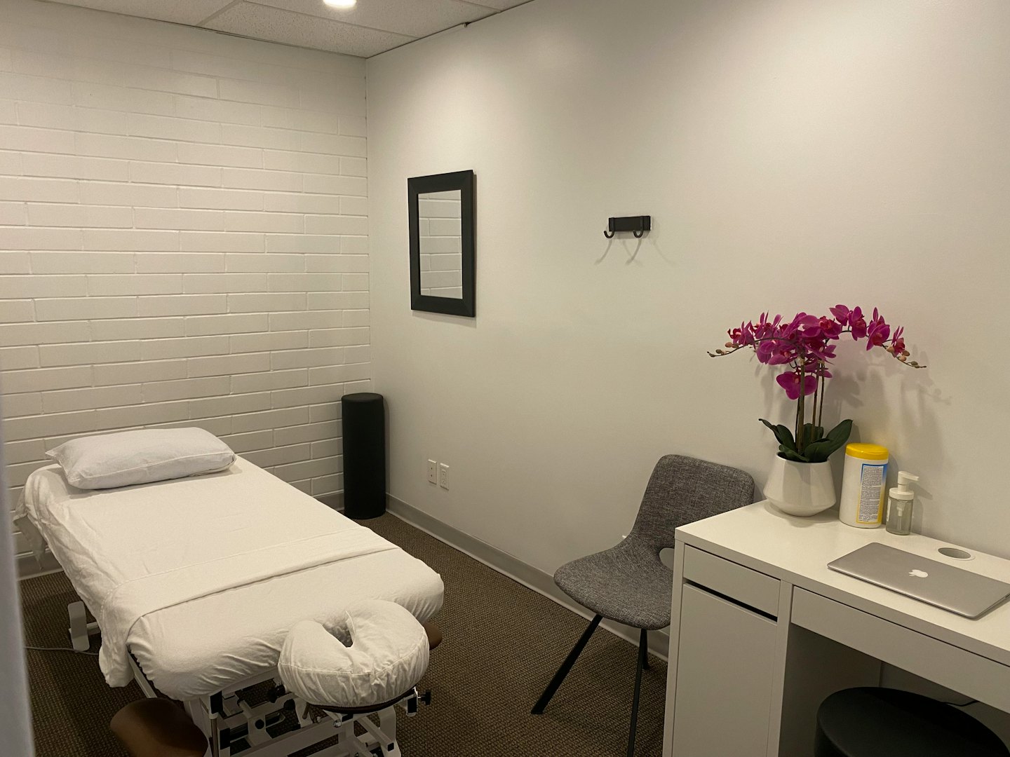 Therapy room with treatment table, chair, and desk.